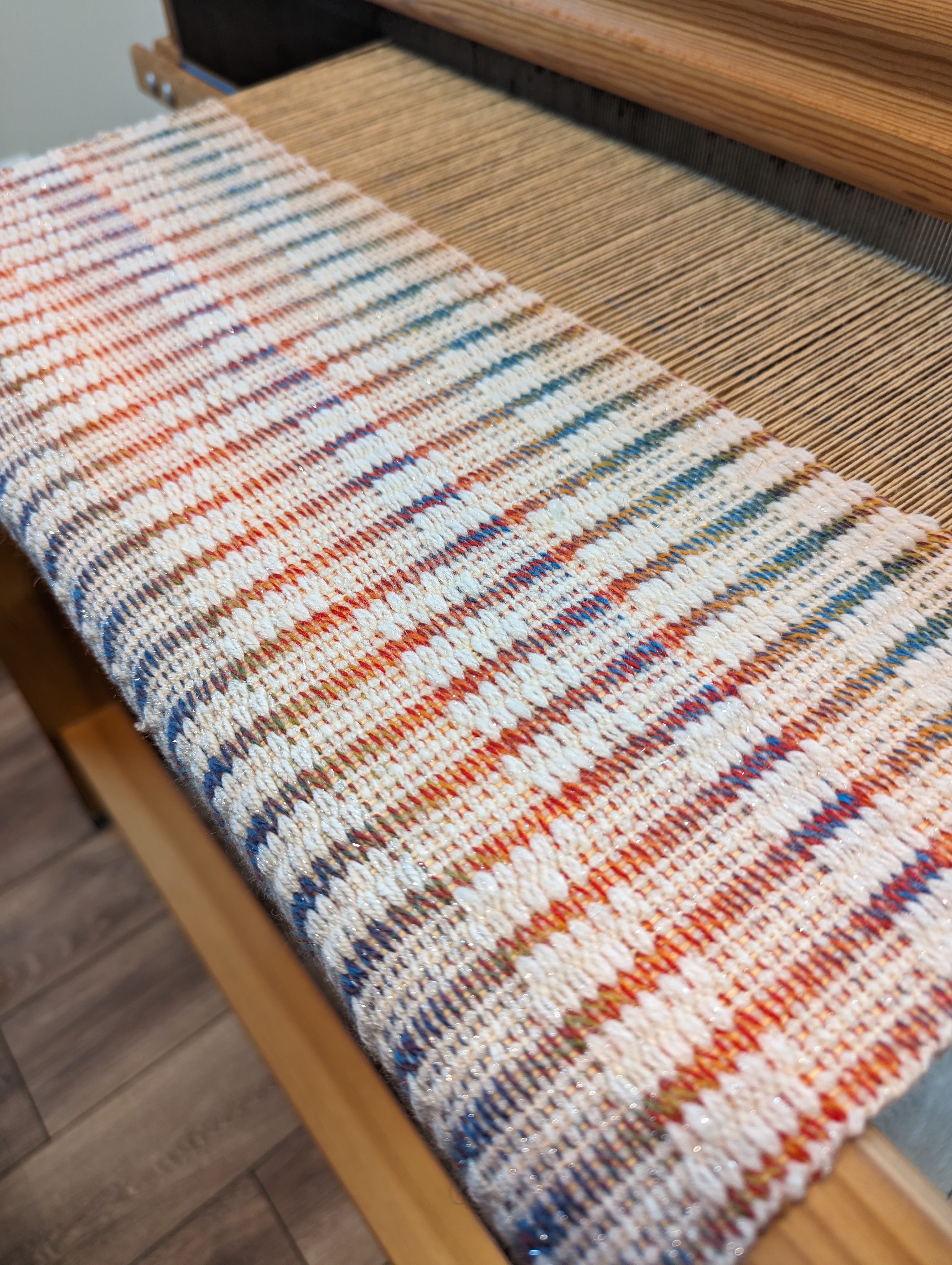 white and rainbow striped weave on the loom